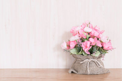 Close-up of pink flower vase on table against wall