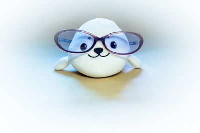 Close-up of stuffed toy wearing eyeglasses over white background