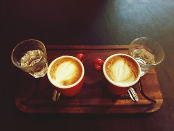 Close-up of coffee cups and drinking glasses on table