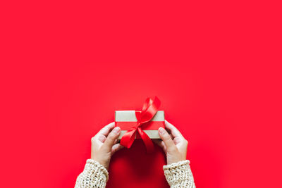 Midsection of man holding red box against colored background