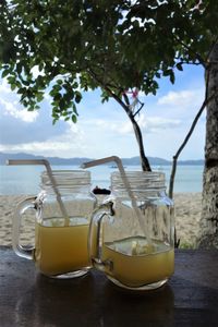 Close-up of drink on table at beach against sky