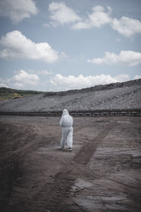 Rear view of worker in protective clothing at mining industry against sky