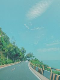 Road by trees against blue sky