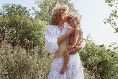 Woman holding a son among trees 