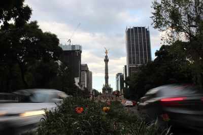 Cars on road by city against sky