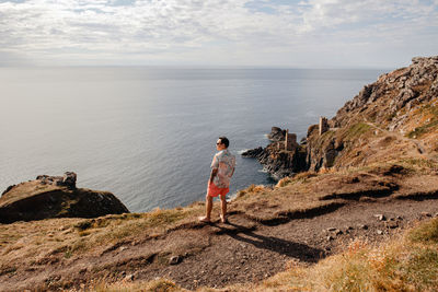 Rear view of man standing on the edge of the cliff 