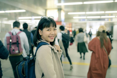 Side view portrait of smiling young woman standing in subway