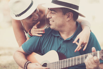 Happy woman listening to man playing guitar