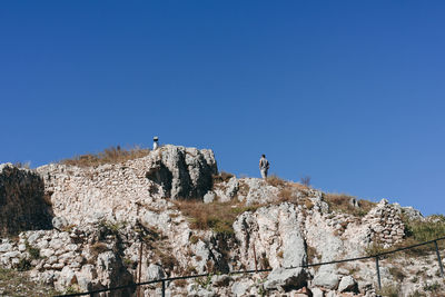 Low angle view of rock formation against clear blue sky