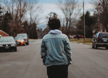 Rear view of man standing on road in city