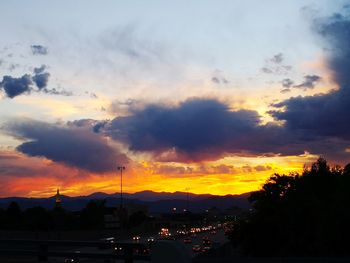 Silhouette city against dramatic sky during sunset