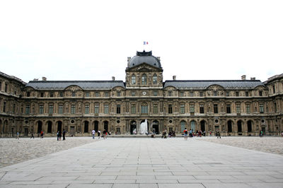 People at louvre museum against clear sky