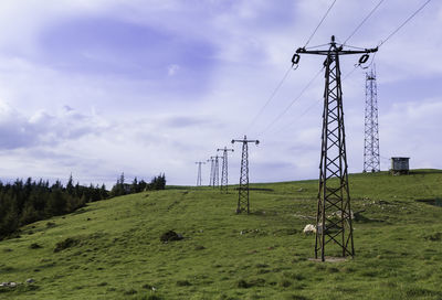 Electricity pylon on field against sky