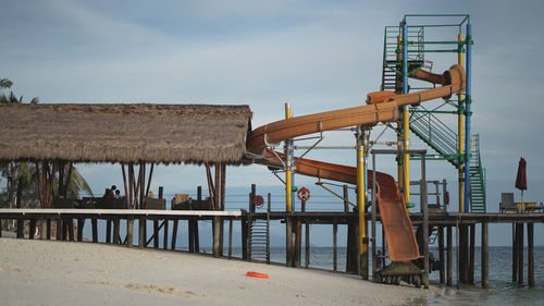 People on pier at beach against sky