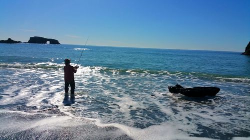 Man standing in sea against clear sky