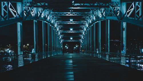 People walking on illuminated footbridge at night
