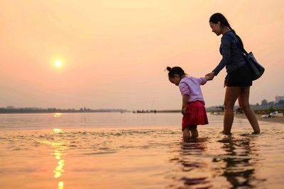 Mother with daughter walking during sunset