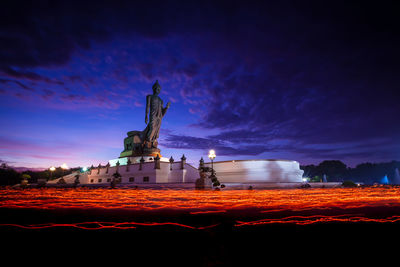 Statue by illuminated building against sky at night
