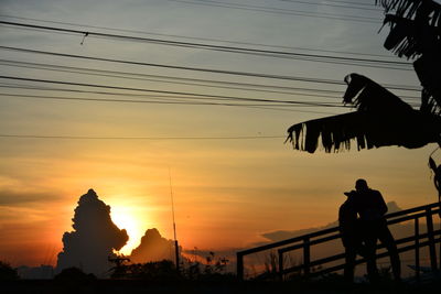 Silhouette people on bridge against sky during sunset