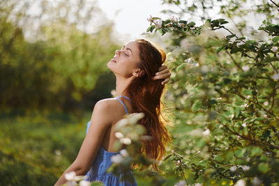 Side view of woman looking away while standing against plants