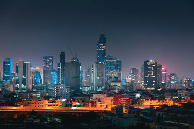 Illuminated buildings in city against sky at night