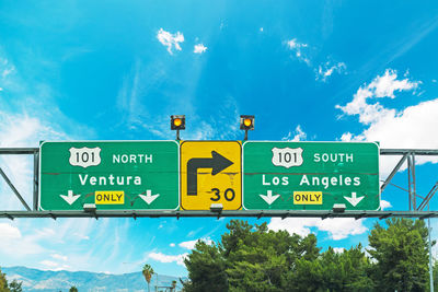 Low angle view of road sign against blue sky