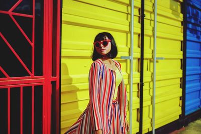 Young woman wearing sunglasses standing against building in city