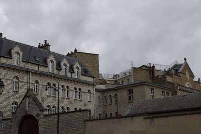 Low angle view of buildings against cloudy sky
