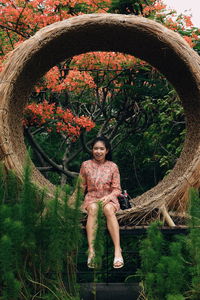 Portrait of smiling young woman standing against plants