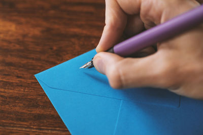Cropped image of man writing on blue envelope