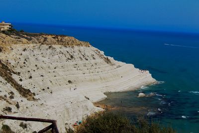 Rock formations by sea against blue sky