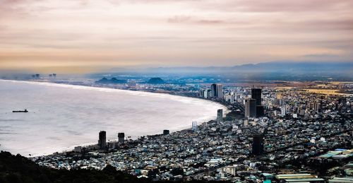 High angle view of city by sea against sky