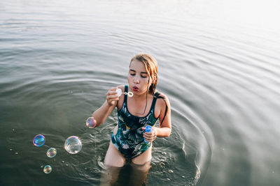 High angle view of girl blowing bubbles in lake