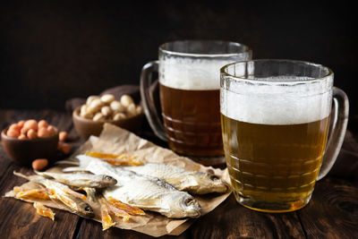 Two glass of beer with foam and snacks on a wooden rustic background. 