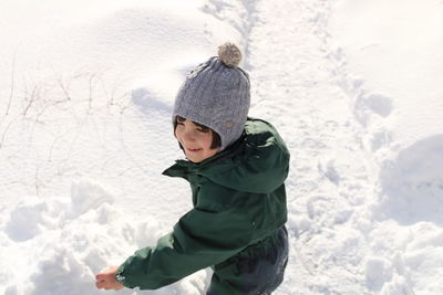 Rear view of boy standing on snow covered field