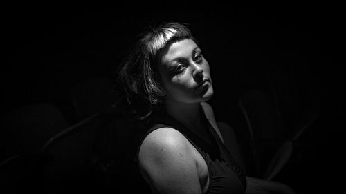Side view of young woman looking away against black background