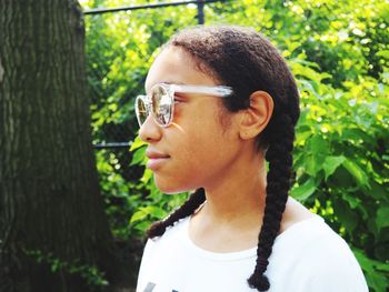 Close-up of young woman wearing sunglasses standing by tree at park