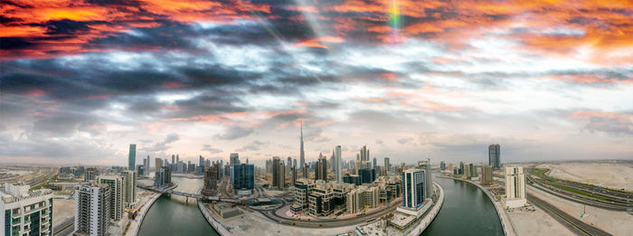 Panoramic view of city buildings against cloudy sky