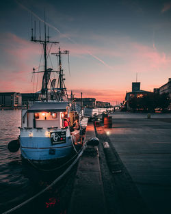 Boats moored at harbor during sunset