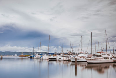 Boats moored at harbor against sky