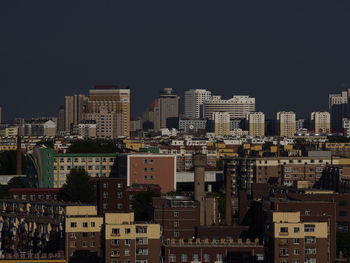 Buildings in city against clear sky at night