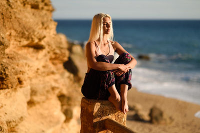 Woman sitting on railing at beach