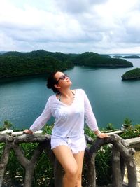 Young woman standing by railing against sea at hundred islands national park