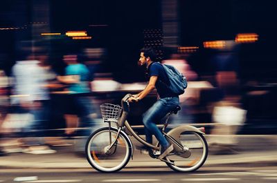 Blurred motion of man riding bicycle on road