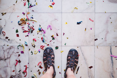 Low section of man standing by confetti on tiled floor