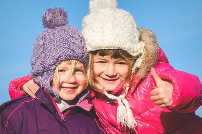 Close-up portrait of happy girls against sky