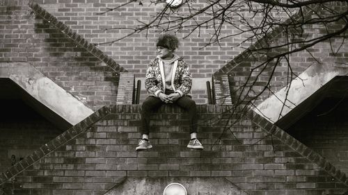 Digital composite image of man sitting on staircase