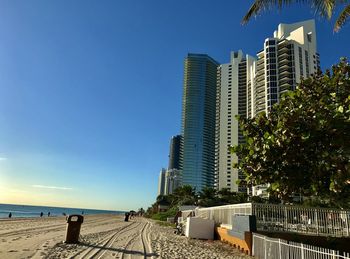 Buildings by sea against blue sky