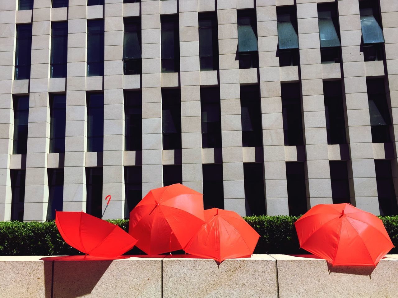 red, umbrella, striped, protection, pattern, in a row, built structure, day, building exterior, architecture, wall - building feature, outdoors, repetition, no people, side by side, wall, multi colored, design, safety, patriotism