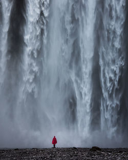 Rear view of man standing against waterfall